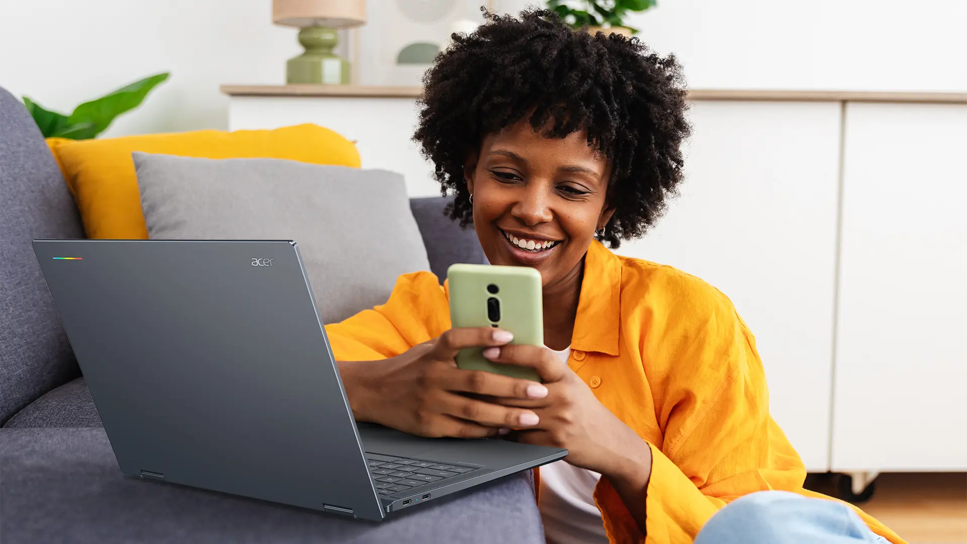 Person using a smartphone beside an Acer Googlebook 14 laptop