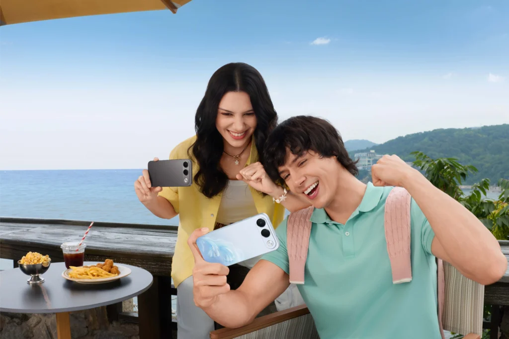 Two people hold OPPO smartphones beside a seaside table